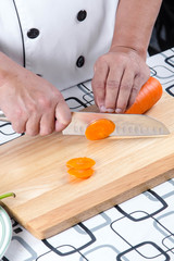 Chef cutting carrot on a wooden board