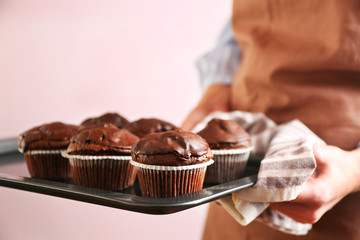 Housewife holding oven-tray with chocolate cupcakes, close up