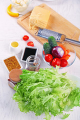 Kitchen utensils and ingredients for salad on table, on light background