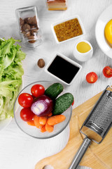 Kitchen utensils and ingredients for salad on table, on light background