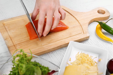 Woman cutting smoked salmon for salad, at kitchen
