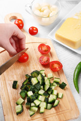 Female hands cutting vegetables for salad, at kitchen