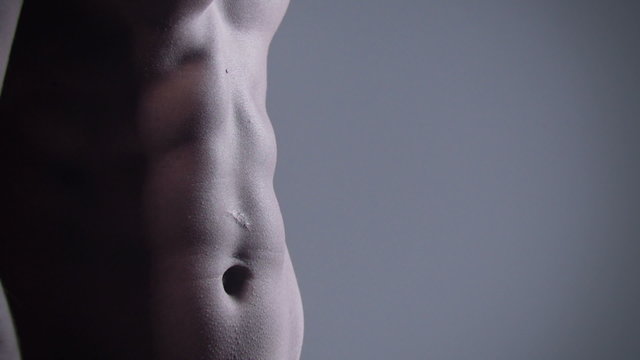 Close up of muscular male body on grey background.