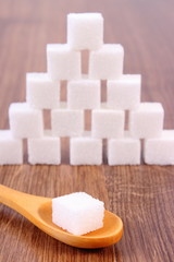Cubes of sugar on wooden background, ingredient for cooking
