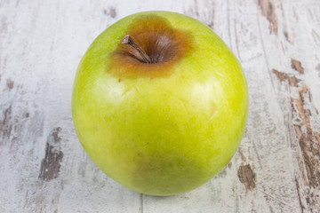 Spoiled apple on old wooden white table