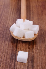 Cubes of sugar on wooden background, ingredient for cooking