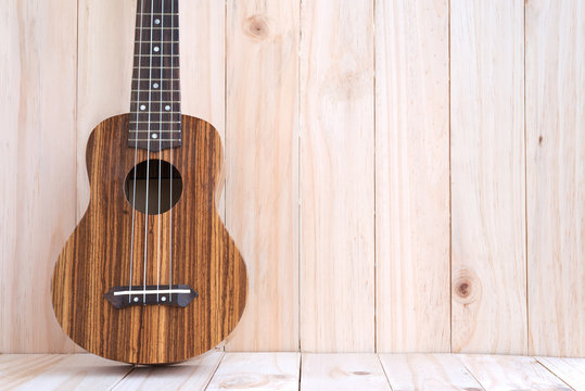 The ukulele on wooden background