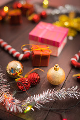 selective focus Christmas background with a red ornament, golden gift box, berries on black wood blackground still life