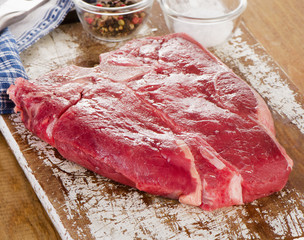 Raw beef steak on  wooden cutting board.
