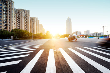 Obraz premium sun skyline and traffic on urban road through city buildings