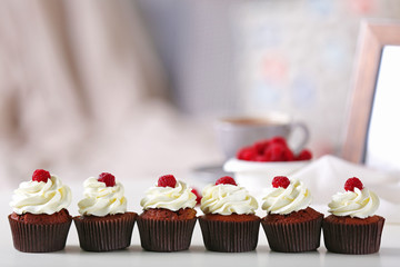 Beautiful chocolate cupcakes with cream and raspberry on table