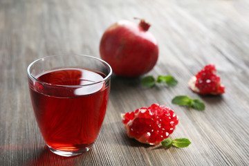 A glass of tasty juice and garnet fruit, on wooden background
