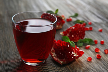 A glass of tasty juice and garnet fruit, on wooden background