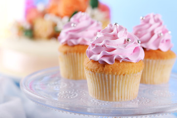 Tasty cupcakes on stand and cake, on table, on color background