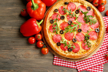 Tasty pizza with salami on decorated wooden table