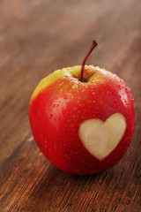 Apple with heart on wooden table
