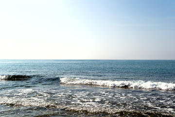 Fototapeta na wymiar Waves breaking on lonely stony beach, forming sprays