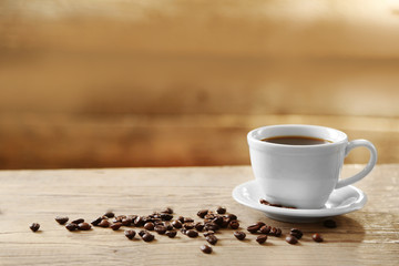 Cup of coffee and coffee grains on wooden background