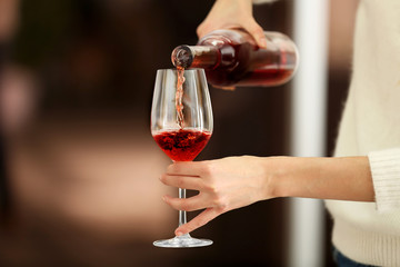 Young woman pouring pink wine into glass on blurred background