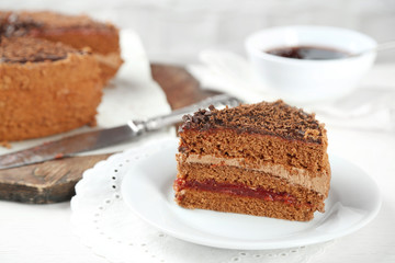 Sliced chocolate cake on wooden table, on light background
