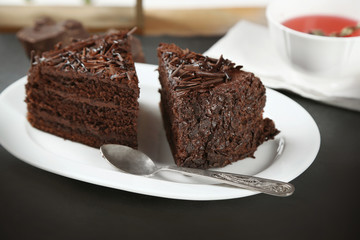 Sliced chocolate cake on wooden table, on light background