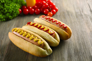 Tasty hot-dogs with vegetables on wooden background