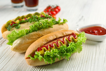 Delicious hot-dog with tomatoes  on white wooden table, close up