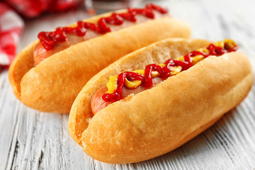 Delicious hot-dogs with chips on white wooden background