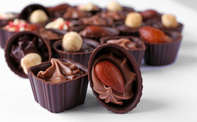 Delicious chocolate candies on white background, close up