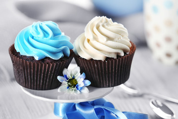Chocolate cupcakes with colourful cream on decorated table , close up