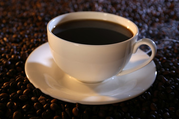 Cup of hot coffee on coffee beans background