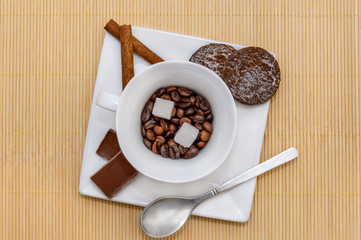 cup with beans of coffee with cookies, chocolate and cinnamon on