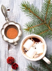 chocolate or cocoa drink with marshmallows in a Christmas cup on the background of spruce
