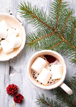 chocolate or cocoa drink with marshmallows in a Christmas cup on the background of spruce