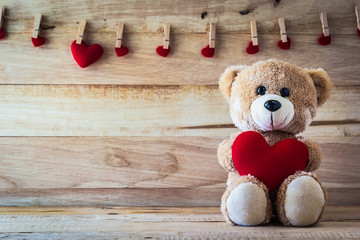 Teddy bear holding a heart-shaped pillow