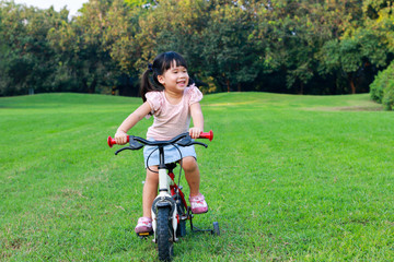 Cute Asian girl enjoy riding bicycle in park