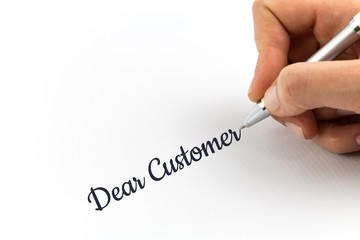 Hand writing "Dear Customer" on white sheet of paper.