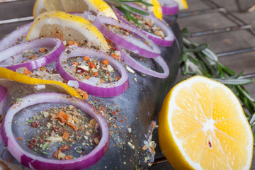 Fish Nelma with lemon, onion and rosemary on a wooden table