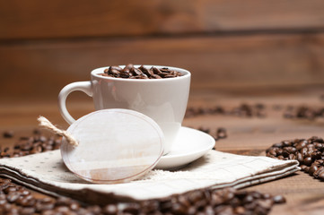 White cup and coffee grains on a wooden surface