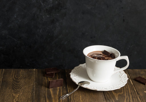 Cup of hot chocolate on vintage wooden background and chocolate slice