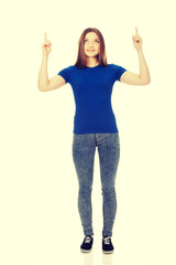 Smiling young woman pointing up.