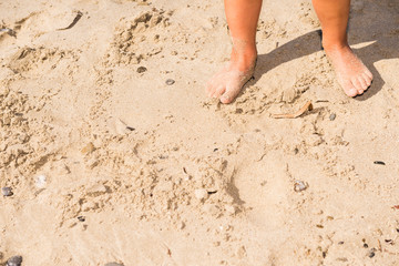 close-up of small feet on the sand in a sunny day