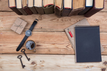 Top view on wooden desktop with books, keys, watch, notepad and