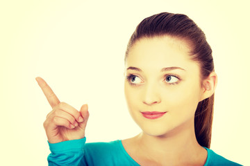 Smiling young woman pointing up.