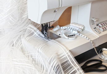 Sewing on a sewing machine at home. Processing edge tulle lace curtains. Household
