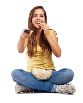 young woman eating popcorn and watching the tv on white