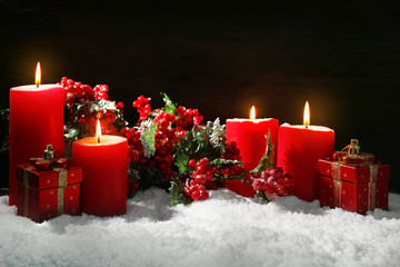 Burning candles, rowan and gift box with snow on wooden background