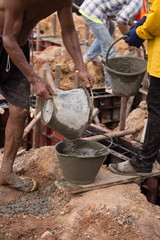 worker pouring concrete from pail bucket