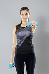sporty woman do her workout with dumbbells, isolated on gray bac