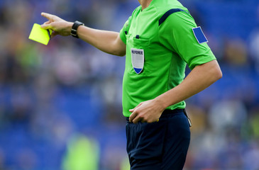 Arbitro de futbol sacando tarjeta amarilla